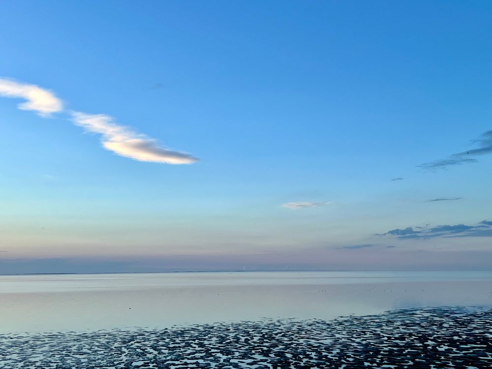 Abendstimmung an der Nordsee, Himmel und Meer in allen Spielarten von blau, lila und orange, im Vordergrund Watt