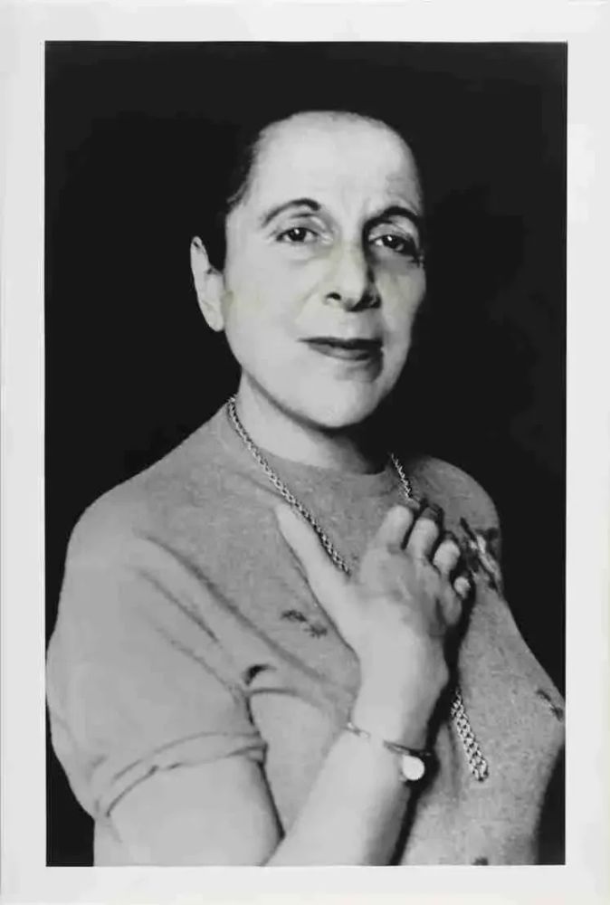 Image: B&W photograph of a B&W photograph Muriel Belcher taken by John Deakin. Francis Bacon Archive, Hugh Lane Gallery | head-and-torso black-and-white photo; figure looking towards the camera with body slightly turned away, the right shoulder being more forward than the left; dark hair lost in the black background, short-lseeved top, chain necklace, right hand on chest, small watch on wrist; inscrutable demeanour • “On view in the Francis Bacon Studio display cases • Curated by AnneMarie Saliba    Bacon’s Portraits of Women explores the artist’s portraits of Henrietta Moraes, Muriel Belcher and Isabel Rawsthorne, three women who were among Bacon’s circle of friends in 1960s Soho, London, and who inspired some of his greatest work.    In London, Bacon often spent his evenings in the Colony Room, a bar owned by Muriel Belcher, which she ran from 1948 to 1979 until her death. Recognising that Bacon was an asset for her business, she gave him a weekly allowance of 10 pounds and provided…”