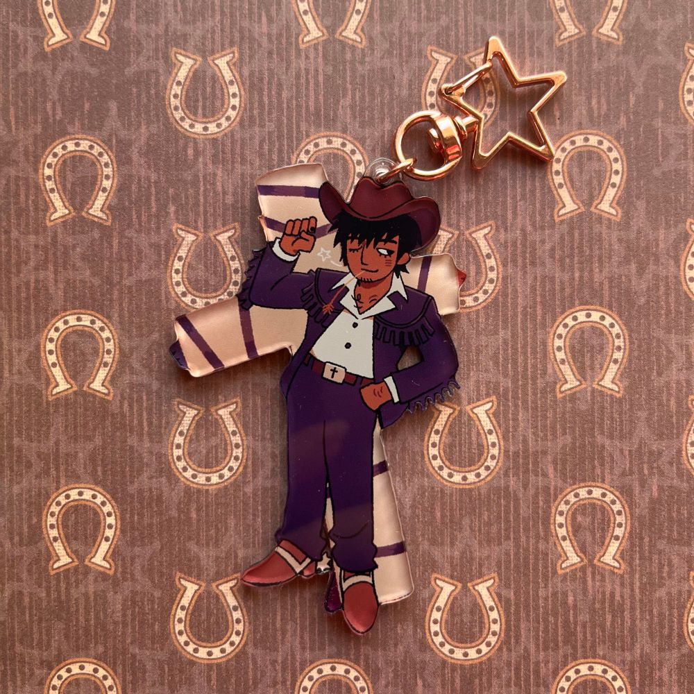cowboy wolfwood (from trigun) keychain. he has spurs, a cowboy hat and fringe on his coat.