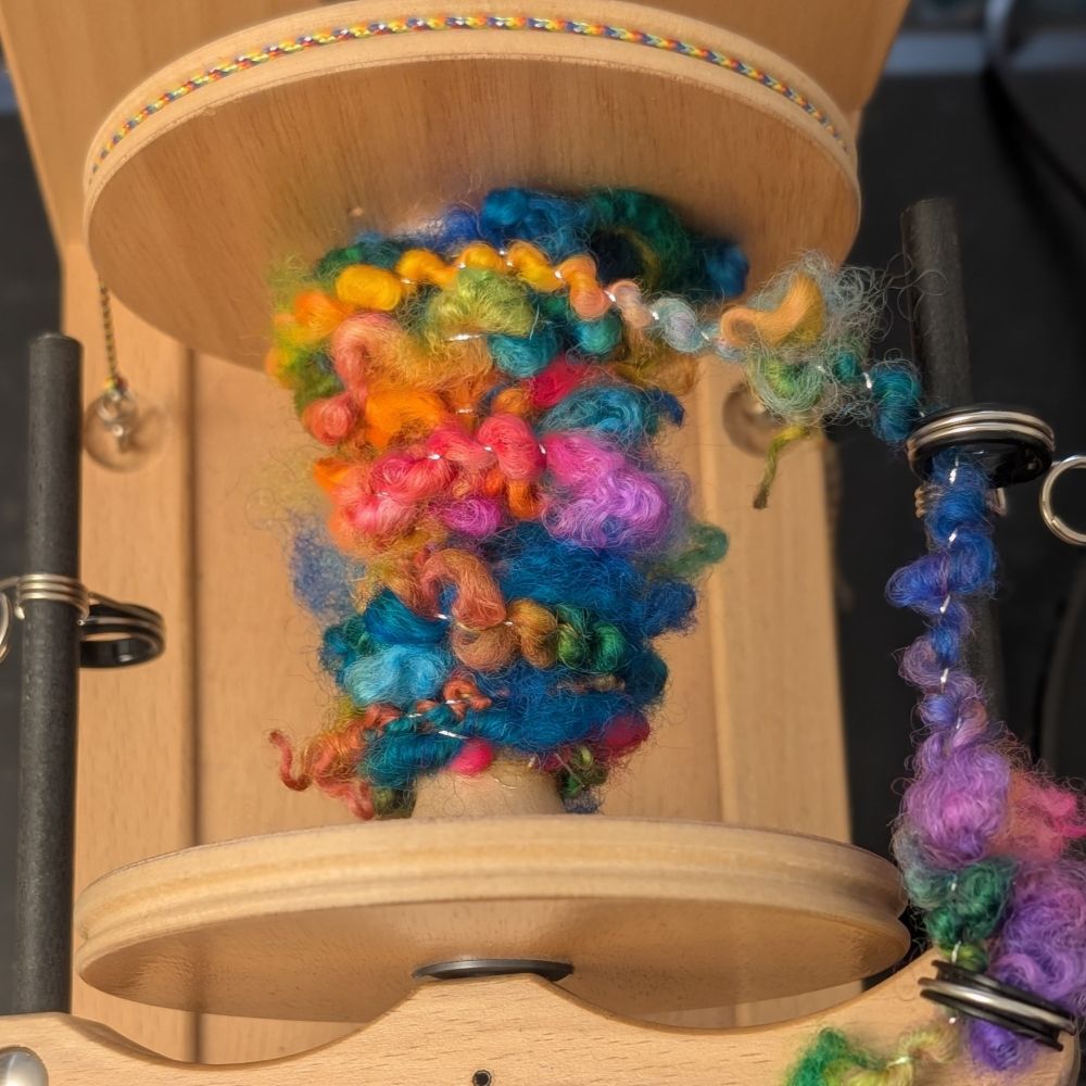 The start of the bobbin showing some of the curly locks poking out as it's plied. 