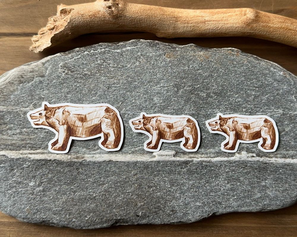 Stickers of brown bears on a flat rock, one is larger than the two that follow