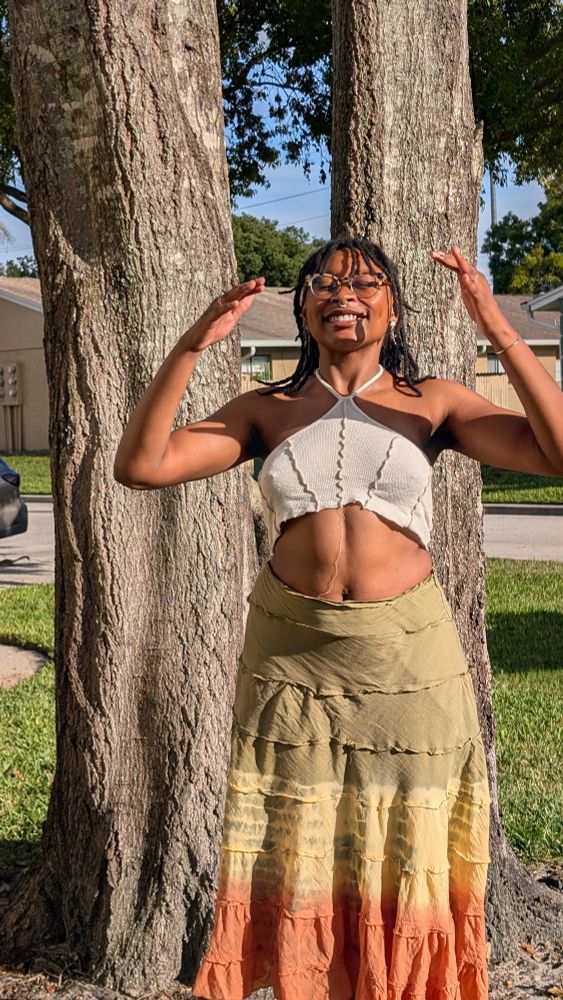 Me in the same outfit standing in front of the same tree and smiling