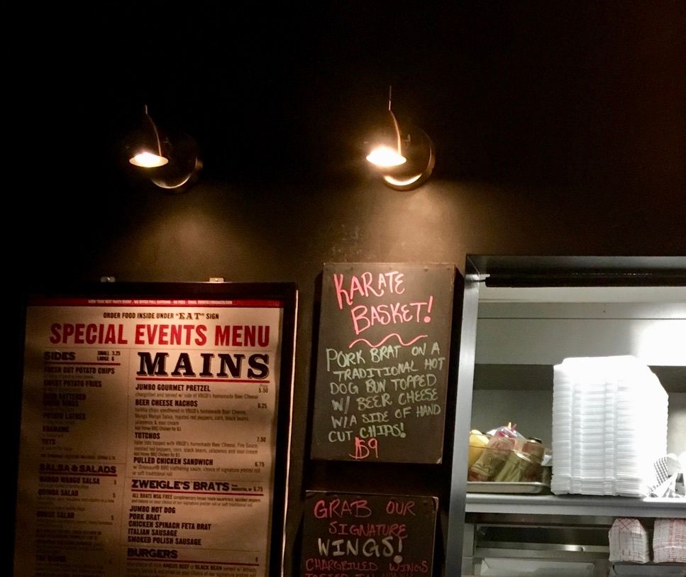 Bar has a "KARATE BASKET!" on their board for the evening. A brat on a bun with cheese. This was 2018.