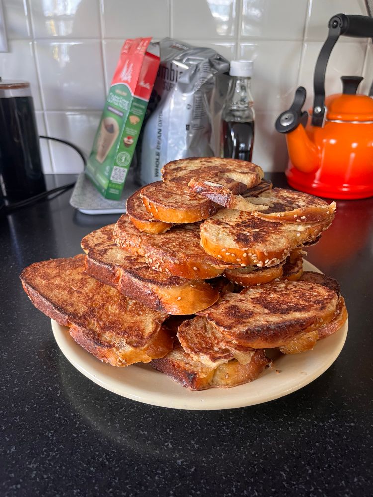 A stack of French toast on a plate in front of a coffee station 
