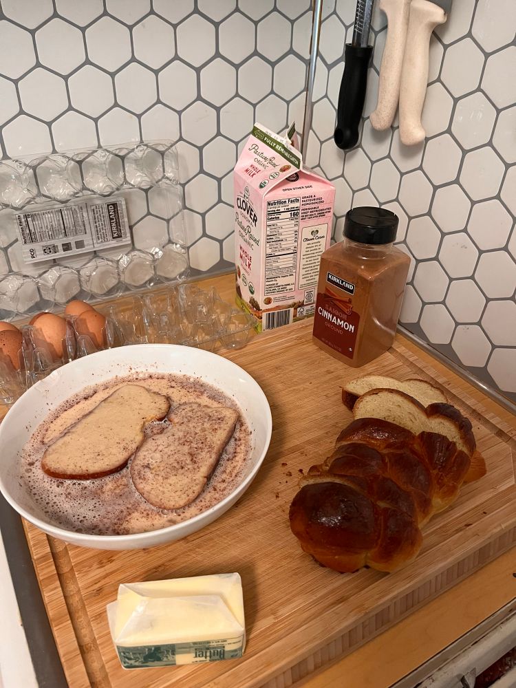 A loaf of challah sliced with French toast soaking. Eggs, milk, cinnamon and butter 