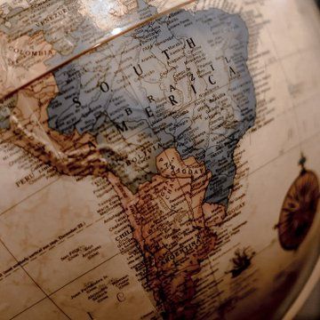 globo terrestre destacando a américa do sul, com foco no brasil e países vizinhos, em tons terrosos e dourados.