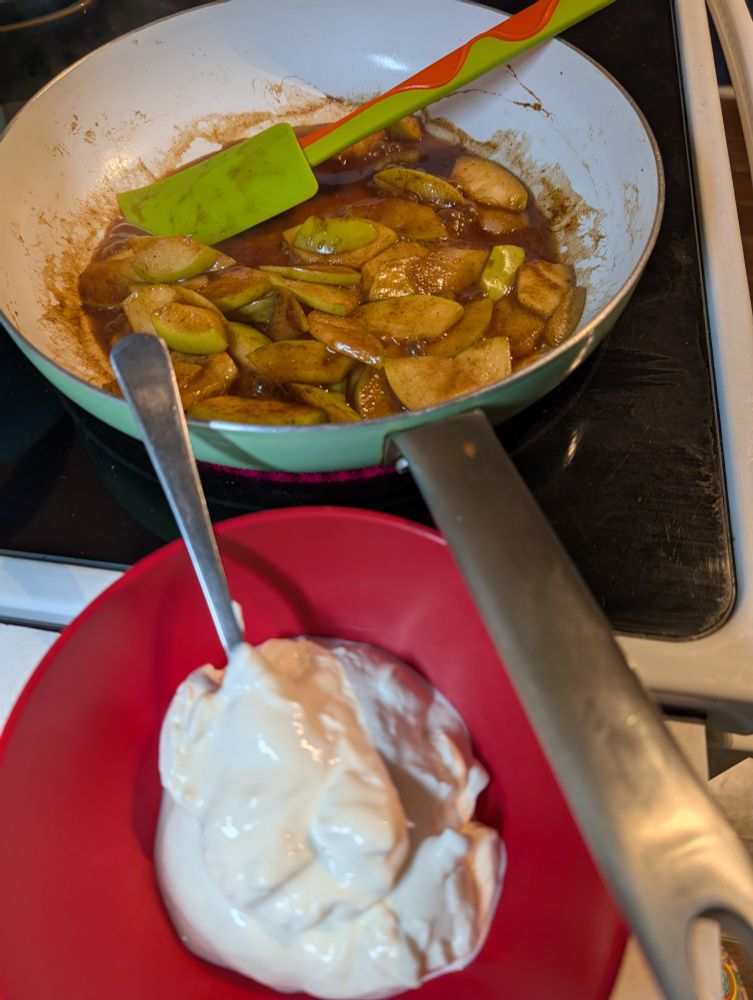 Bowl of yogurt next to a pan with apples cooking