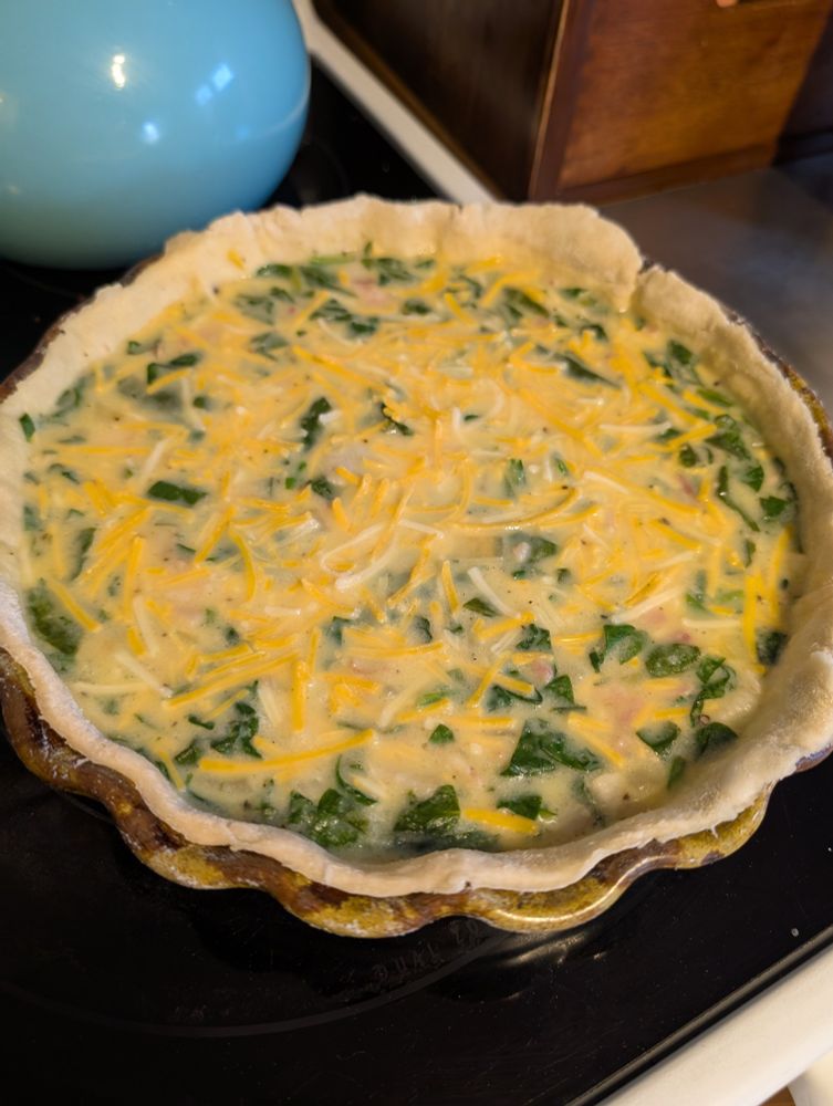 Unbaked spinach cheese and bacon quiche with homemade crust