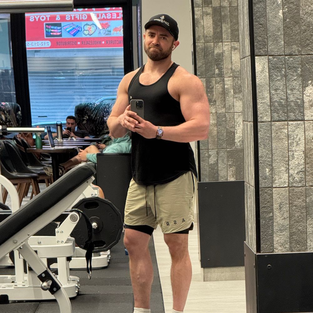 me wearing a tank top and shots standing next to a leg press 