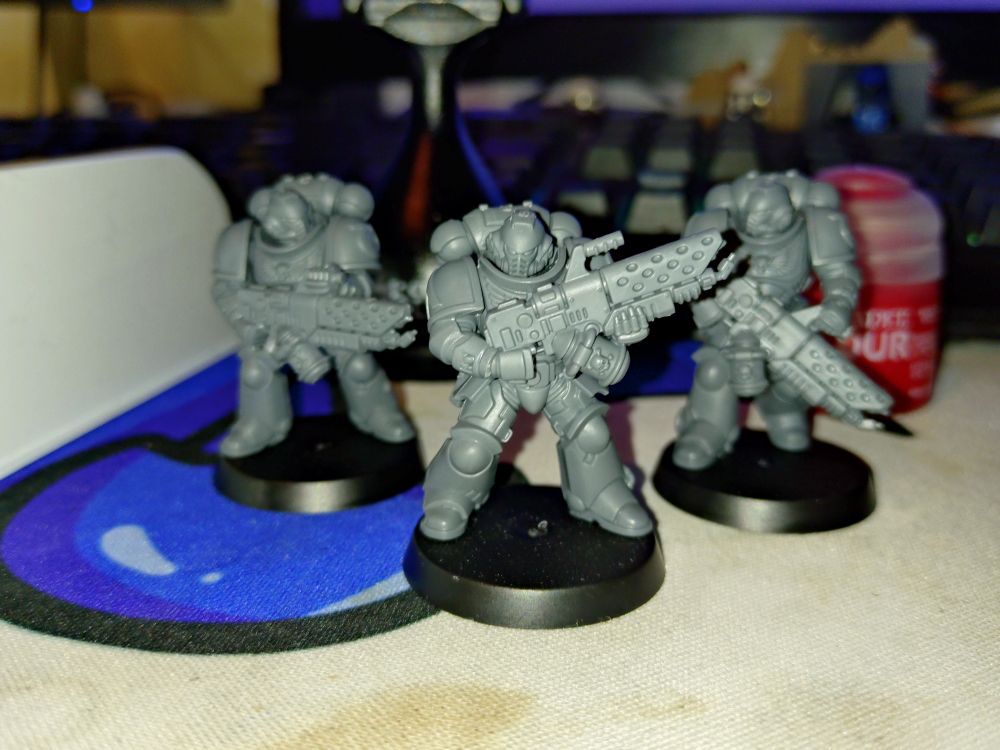 3 unpainted Infernus Space Marines, with a red paint pot and mini painting handle behind them.