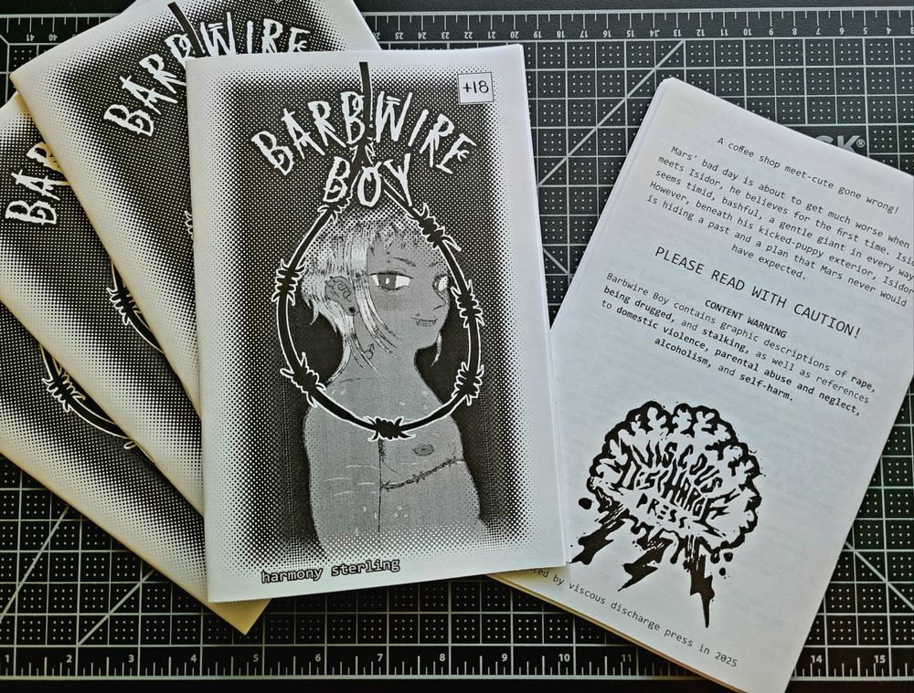 an arranged pile of zines titled "barbwire boy". one is flipped on the back, showing the summary and content warnings.
"A coffee shop meet-cute gone wrong!
Mars' bad day is about to get much worse when he meets Isidor, he believes for the first time. Isidor seems timid, bashful, a gentle giant in every way. However, beneath his kicked-puppy exterior, Isidor is hiding a past and a plan that Mars never would have expected.
PLEASE READ WITH CAUTION!
CONTENT WARNING
Barbwire Boy contains graphic descriptions of rape, being drugged, and stalking, as well as references to domestic violence, parental abuse and neglect, alcoholism, and self harm."