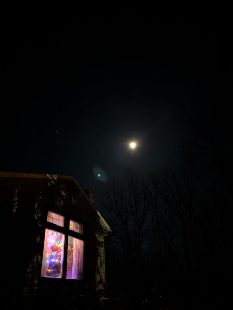 The full moon in a clear sky. In the foreground is a window with colorful lights. 

awooo.
