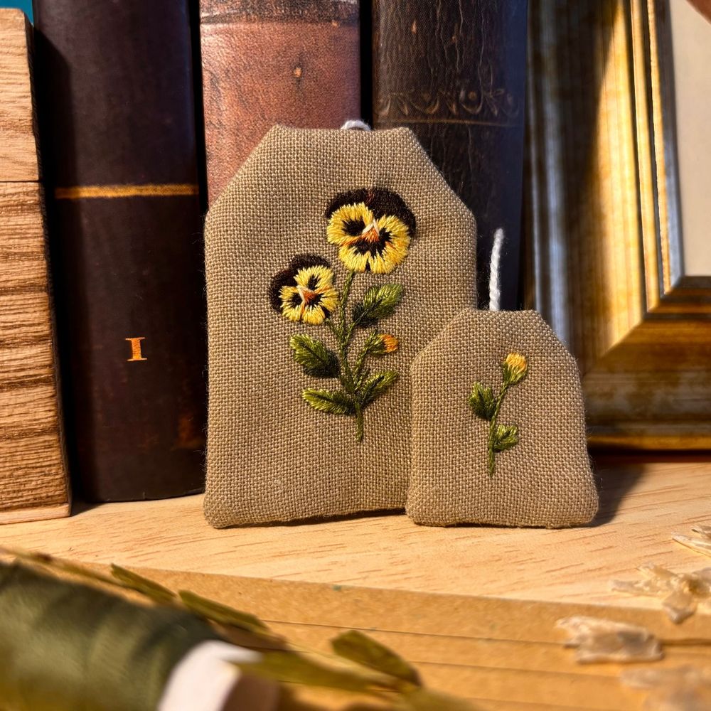 Bookmark shaped as a tea bag, with yellow pansies embroidered on it.
