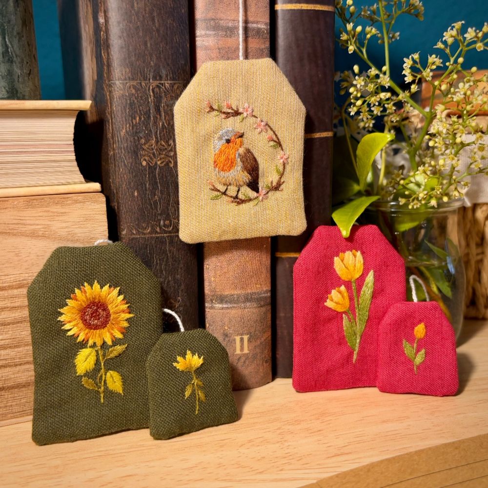 Bookmarks shaped as tea bags. They have embroidery on them: sunflower, robin and tulips.