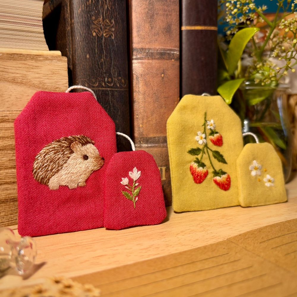 Bookmarks shaped as tea bags. They have embroidery on them: hedgehog and strawberries.