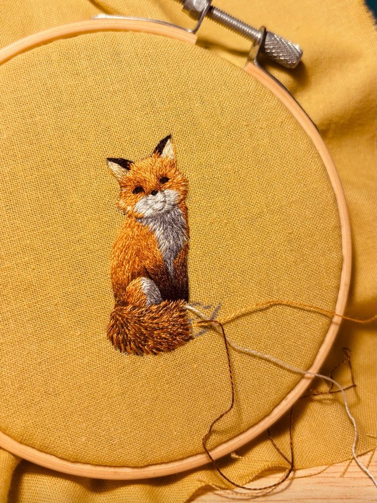 Embroidered fox on light green fabric.