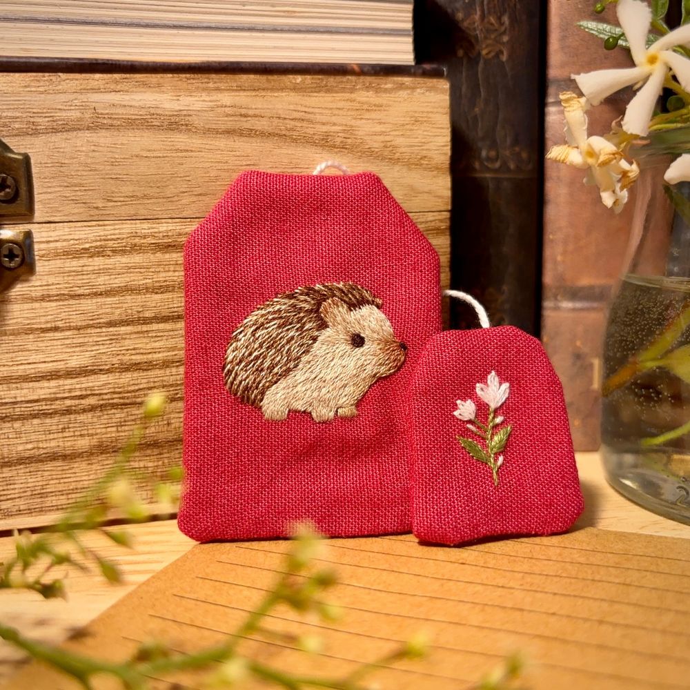 Bookmark shaped as a tea bag, with a hedgehog embroidered on it.