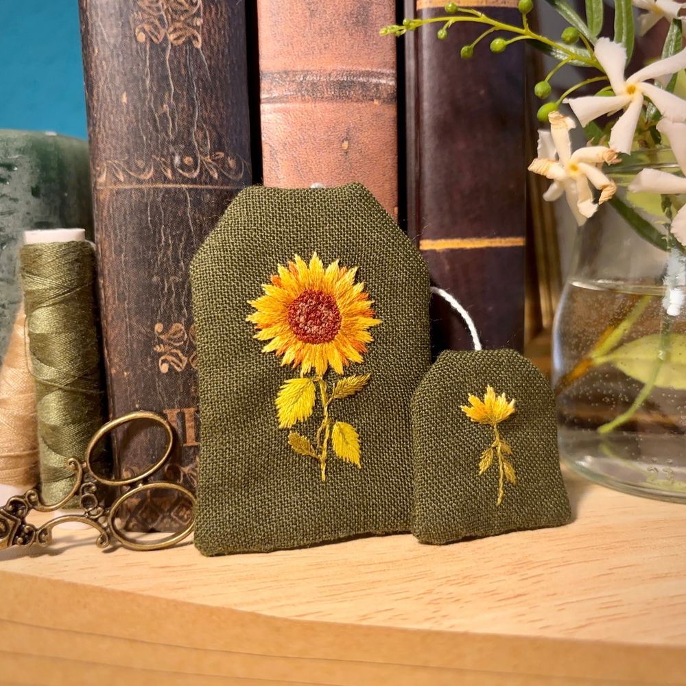 Bookmark in the shape of a tea bag, with a sunflower embroidered on it.