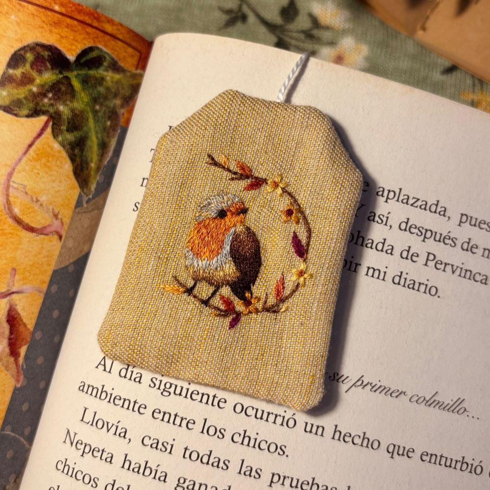 A robin embroidered on a bookmark shaped as a tea bag.
