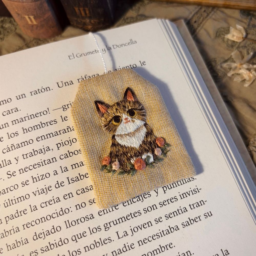 Bookmark in the shape of a tea bag, with a cat embroidered on it.