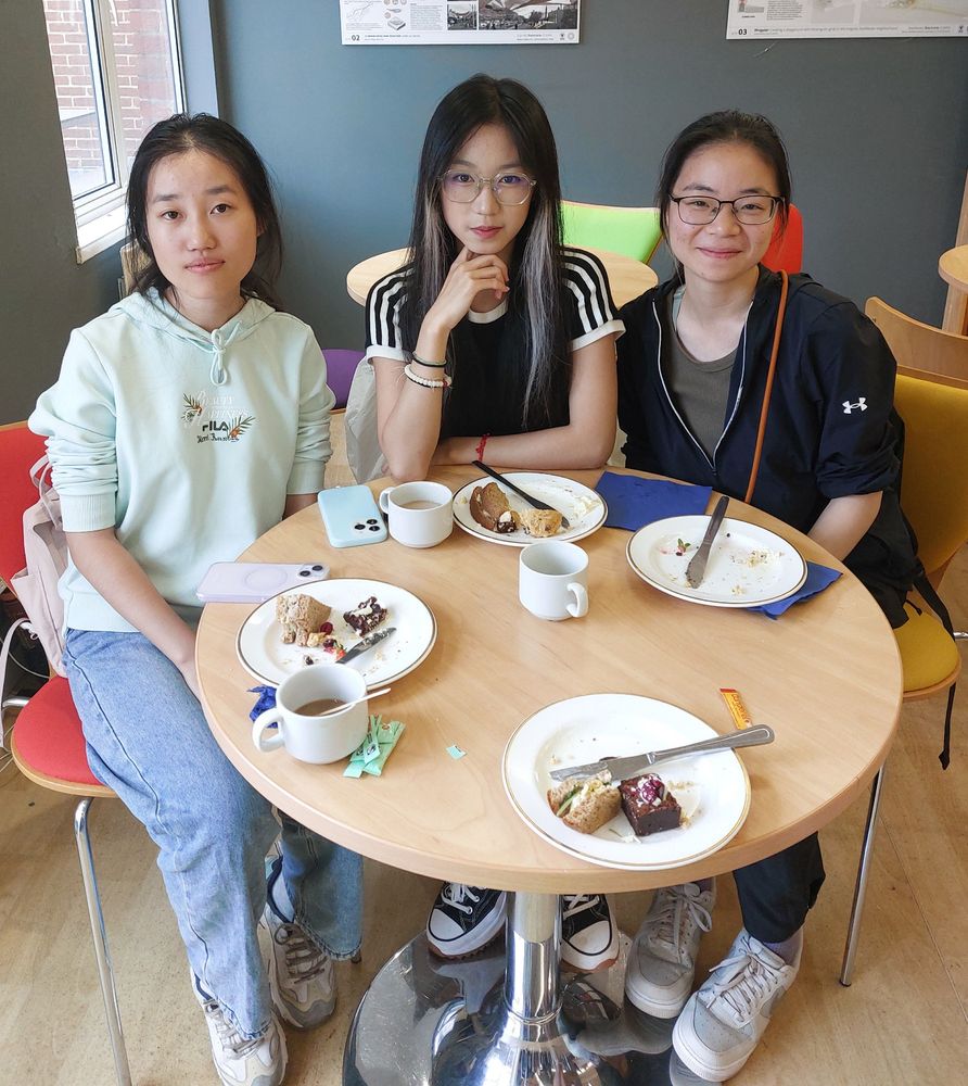 Sussex International Junior Research Associates sitting at a table smiling with their Afternoon Tea. 