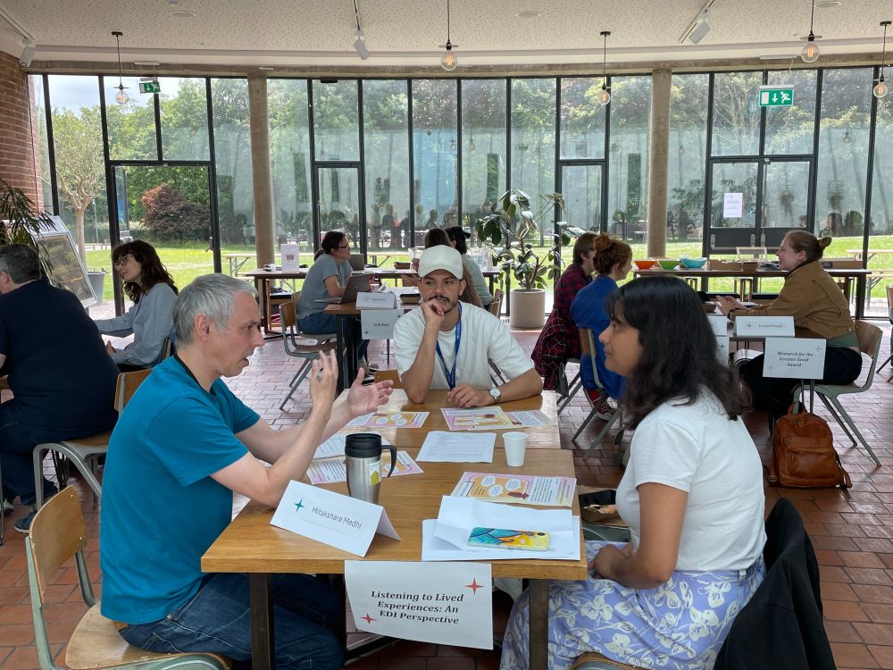 Table of people talking. In the background are more tables with people talking. 