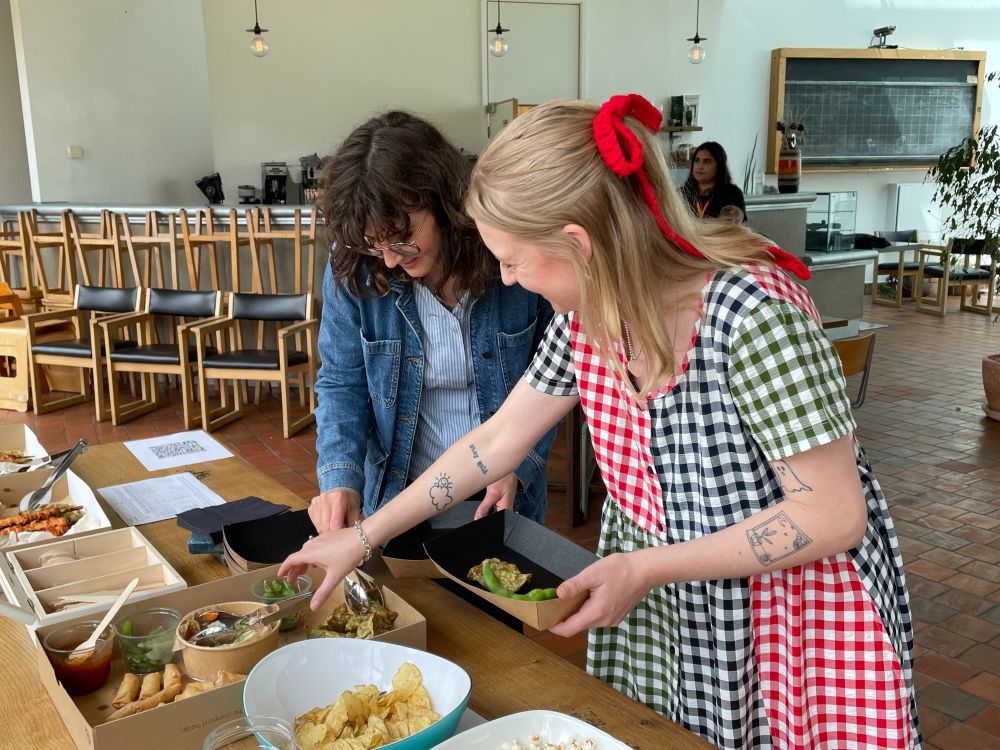 Two people smiling and helping themselves to food. 