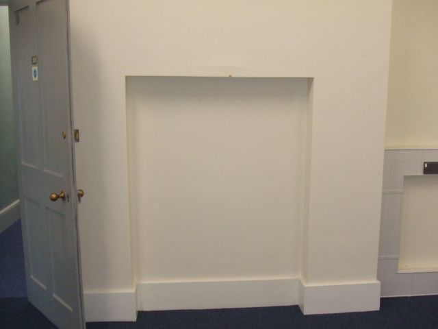 A blocked up hearth, with a door to the side.