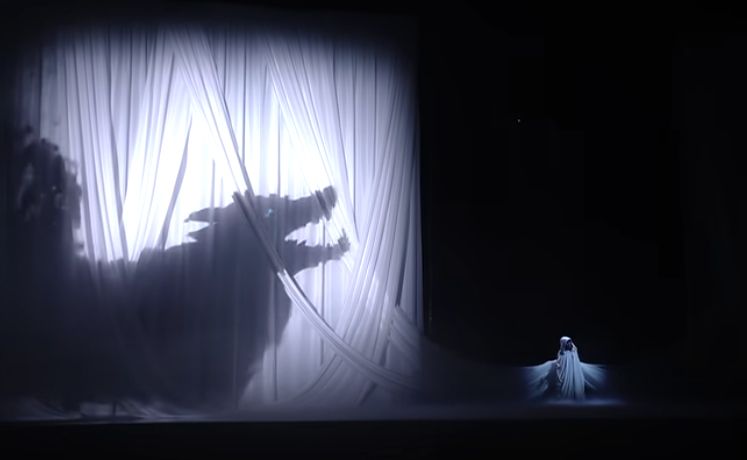 A shadow of a wolf beamed onto lit up white curtains behind Tiffany Aris.