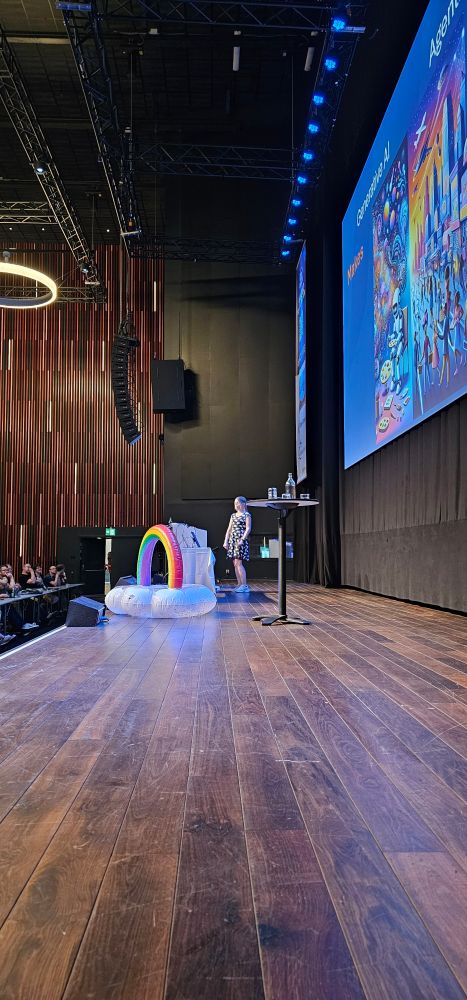 Barbara in her cloud suit on stage with a rainbow blow up toy