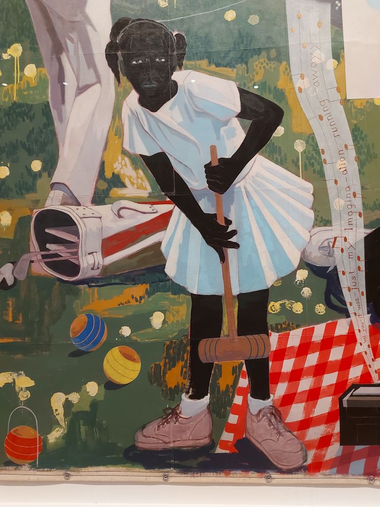 A Black girl holds a croquet mallet. She's wearing a white top and skirt, and pink trainers. She stares out at us, frozen in the moment. She and her family are having a picnic in the park. There is a red-and-white gingham tablecloth, and music, like a translucent scarf, is floating upwards from a boombox.