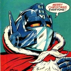 Optimus Prime wearing a Santa outfit pulling down a fake beard and saying "merry Christmas everyone,".