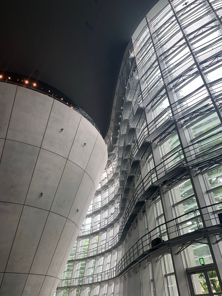 ガラスの曲面と巨大な円錐形のコンクリート構造の美術館内の風景