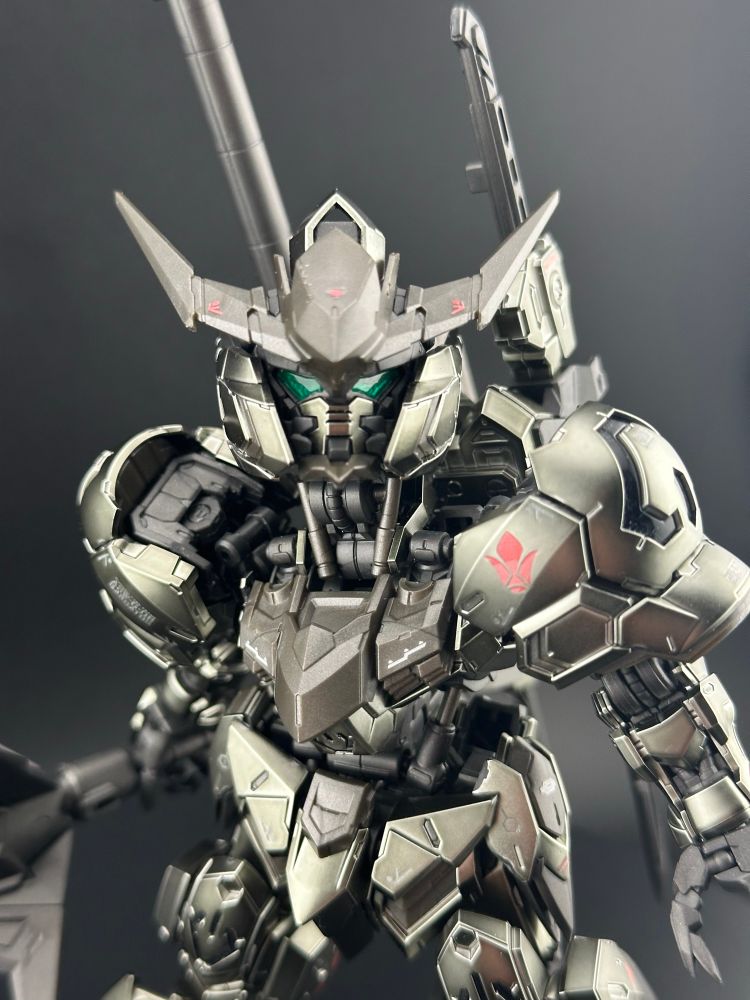 A light box photo of the master grade super deformed Barbatos (Iron-Blooded Coating) Gundam plastic model kit, from Iron-Blooded Orphans. Barbatos is looking upwards at the camera, which is focused on the head and torso