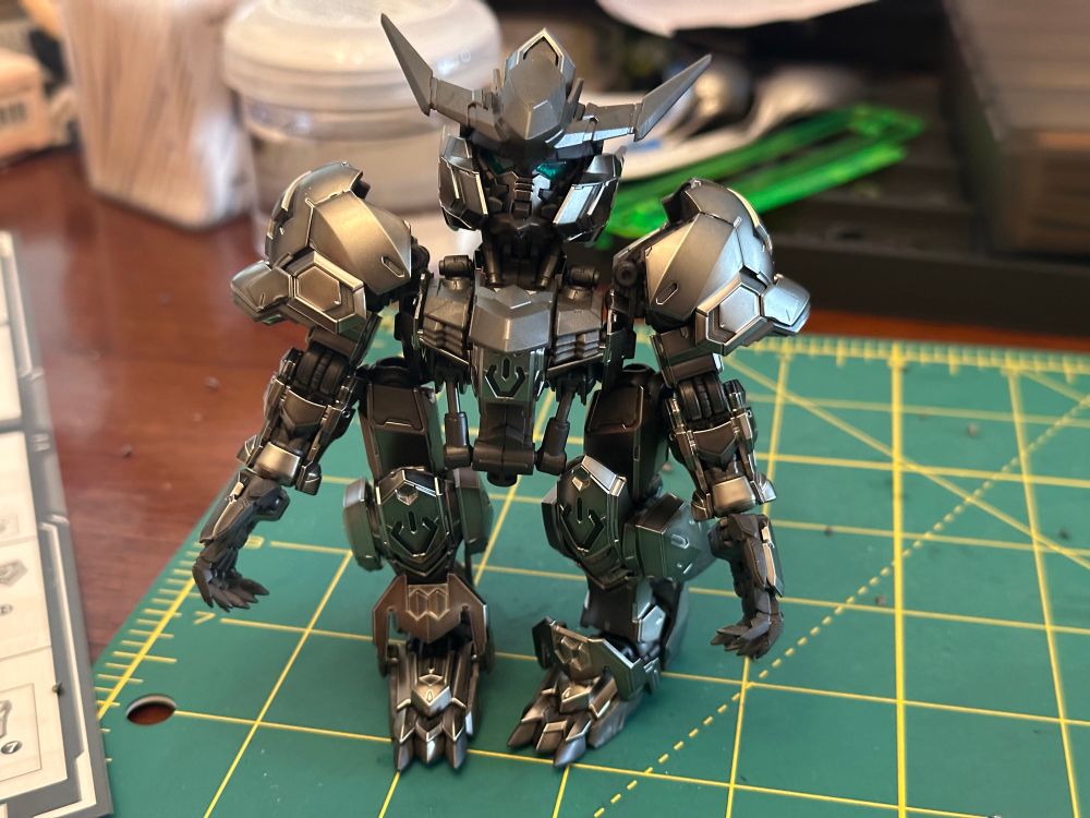 A photo of the mostly constructed master grade super deformed Barbatos Gundam plastic model kit. The upper body is precariously balanced on the assembled legs, as the hips have not been built yet 
