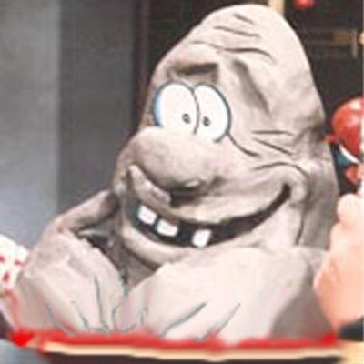It's a large blob of gray clay shaped to look like a head and arms with big goofy features. Someone has placed pieces of paper on it to make eyes and a few teeth. It is from the children's show "The Gigglesnort Hotel".
