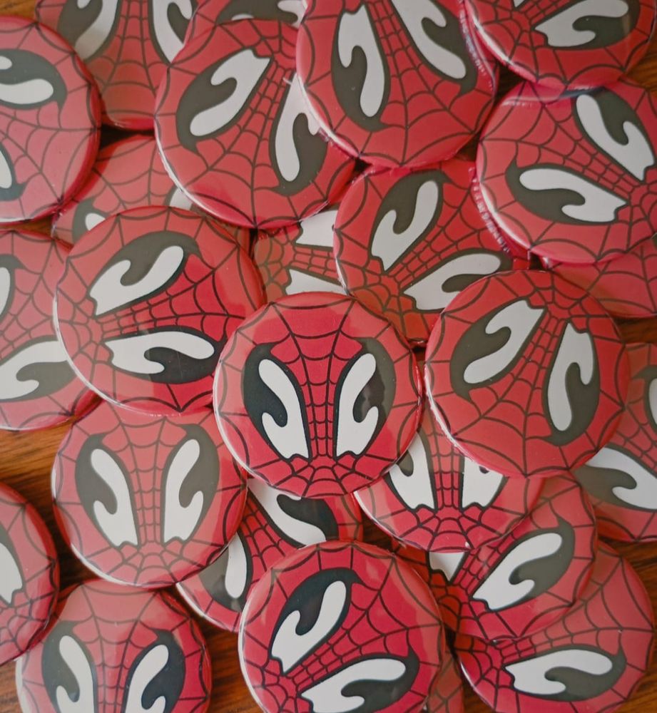 foto de vários bottons com o desenho do logo da Antártica com as teias do Homem-Aranha