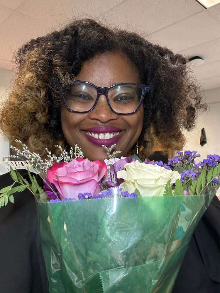 Picture of Caprice smiling and holding a bouquet of flowers