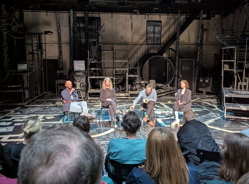 Photo shows the panel with the four participants mentioned in the post in front of an industrial backdrop setting of the Malersaal.