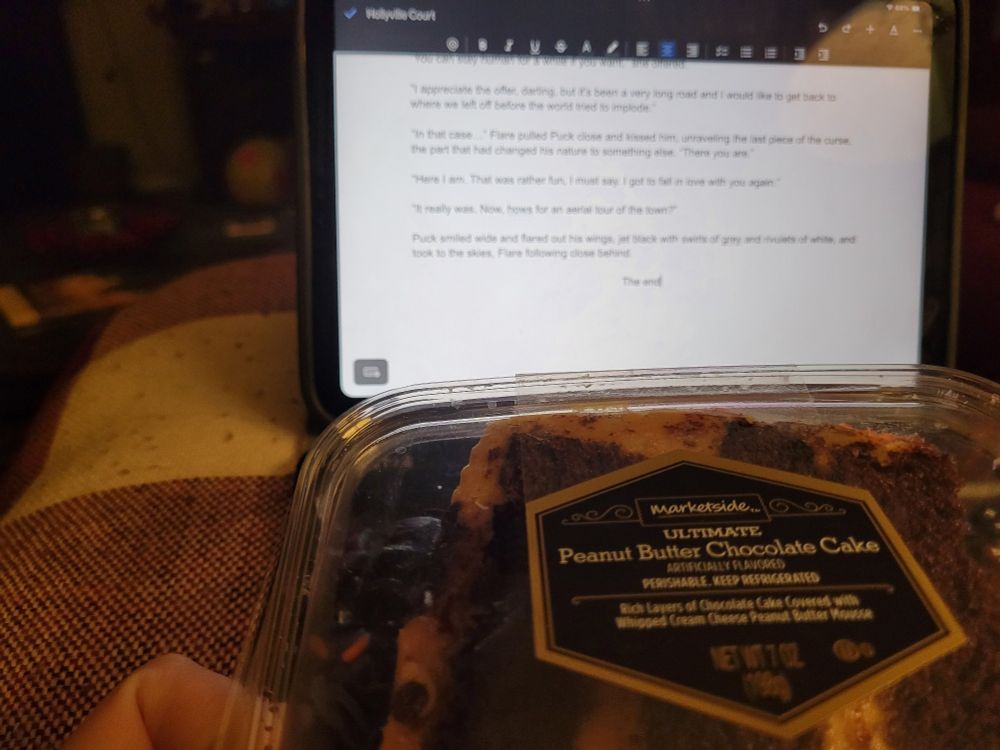 A piece of peanut butter and chocolate cake on front of a tablet with a finished story