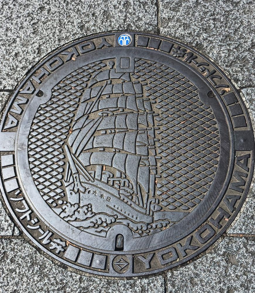Japanese municipal manhole cover depicting a large sailing ship and, in Roman alphabet, "Yokohama" 