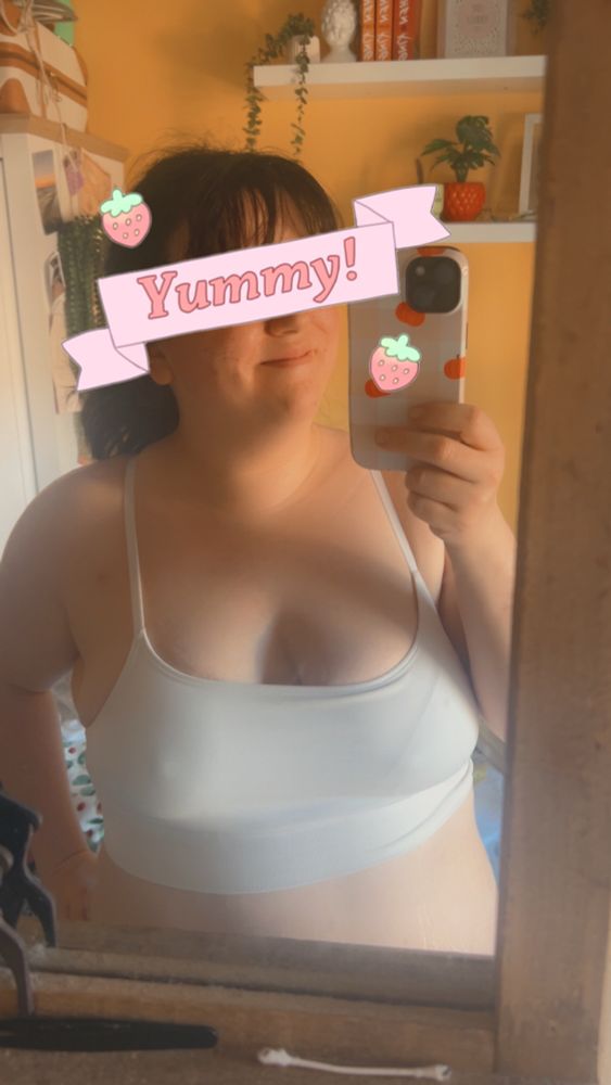 A mirror selfie of me with a ponytail in my hair. I’m wearing a while bralette and my nipples are kinda poking through. Across my eyes is a banner that says “yummy” to keep my mysterious 
