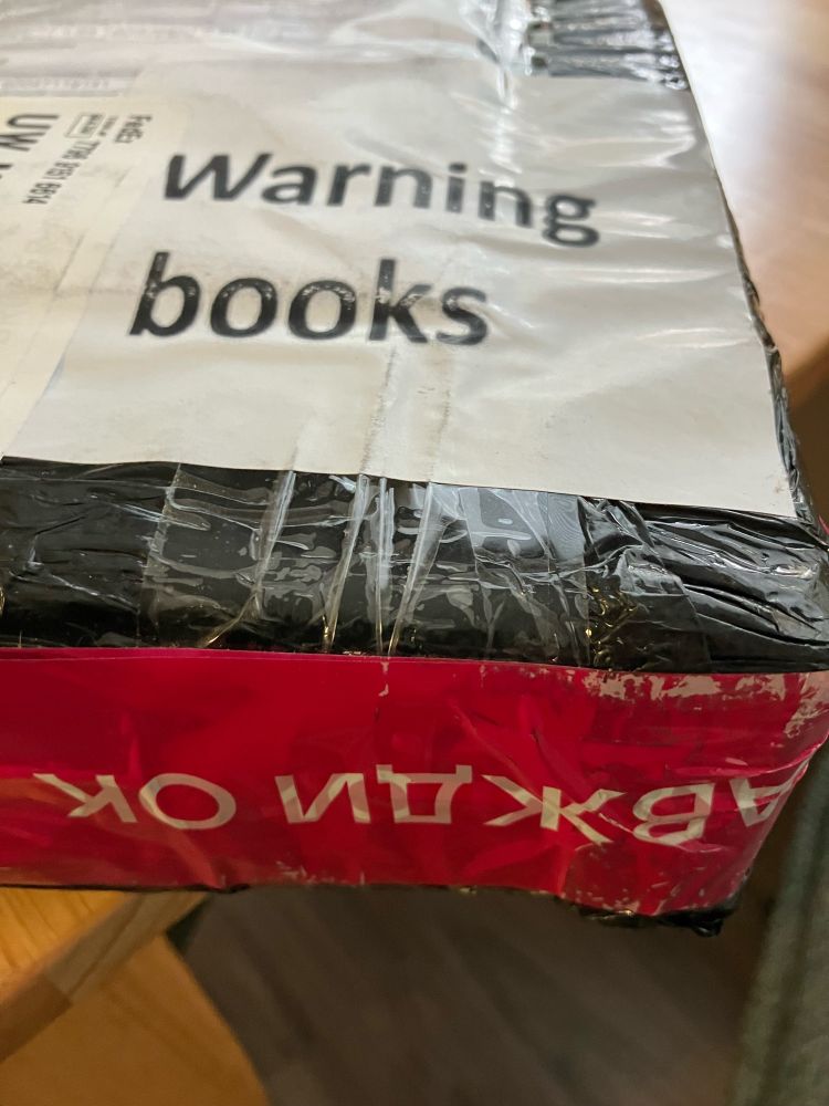 A sticker that says "Warning Books" on a tightly wrapped package