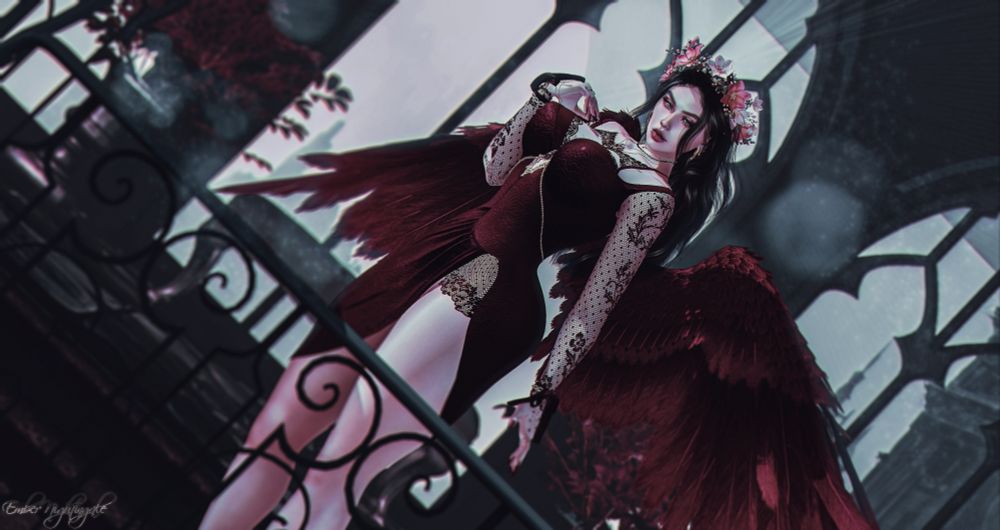 A woman stands dressed in a deep crimson knee length dress, beads adorn her bust, giving the dress shape. Crimson wings spread out behind her. Dark locks toss by an unseen force while the crown of red flowers on her head remains unmoved and in place. She exudes power, demands authority and stands gazing over the railing to the crowd below. The gothic style window behind her pours light over her form, a stunning and terrifying being.