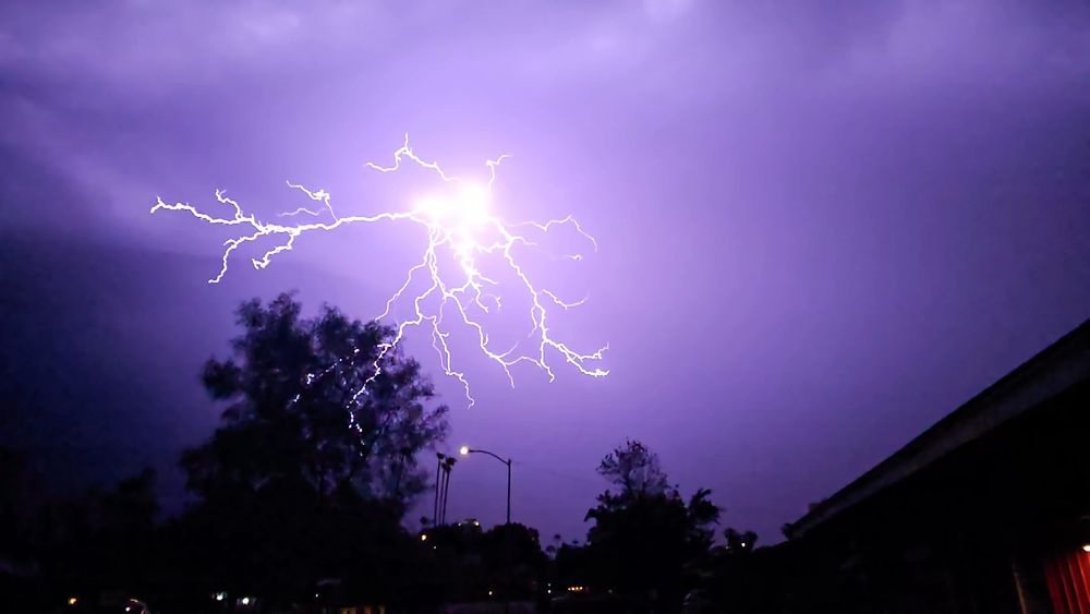 Lightning spreads across a purple sky