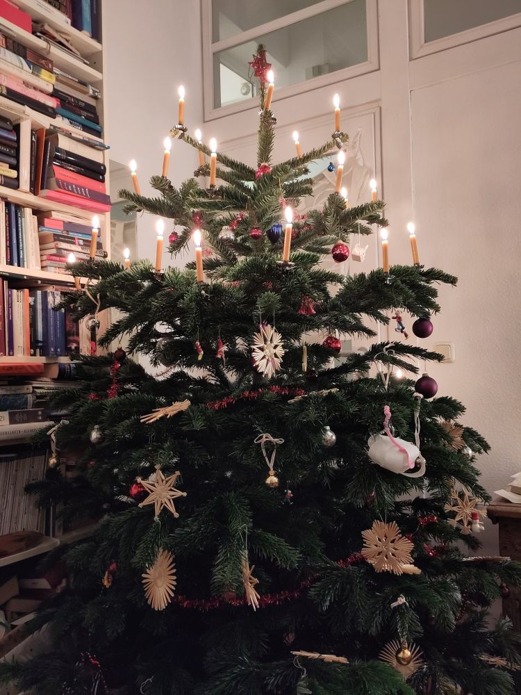 Photo of a Christmas tree with straw stars and real candles