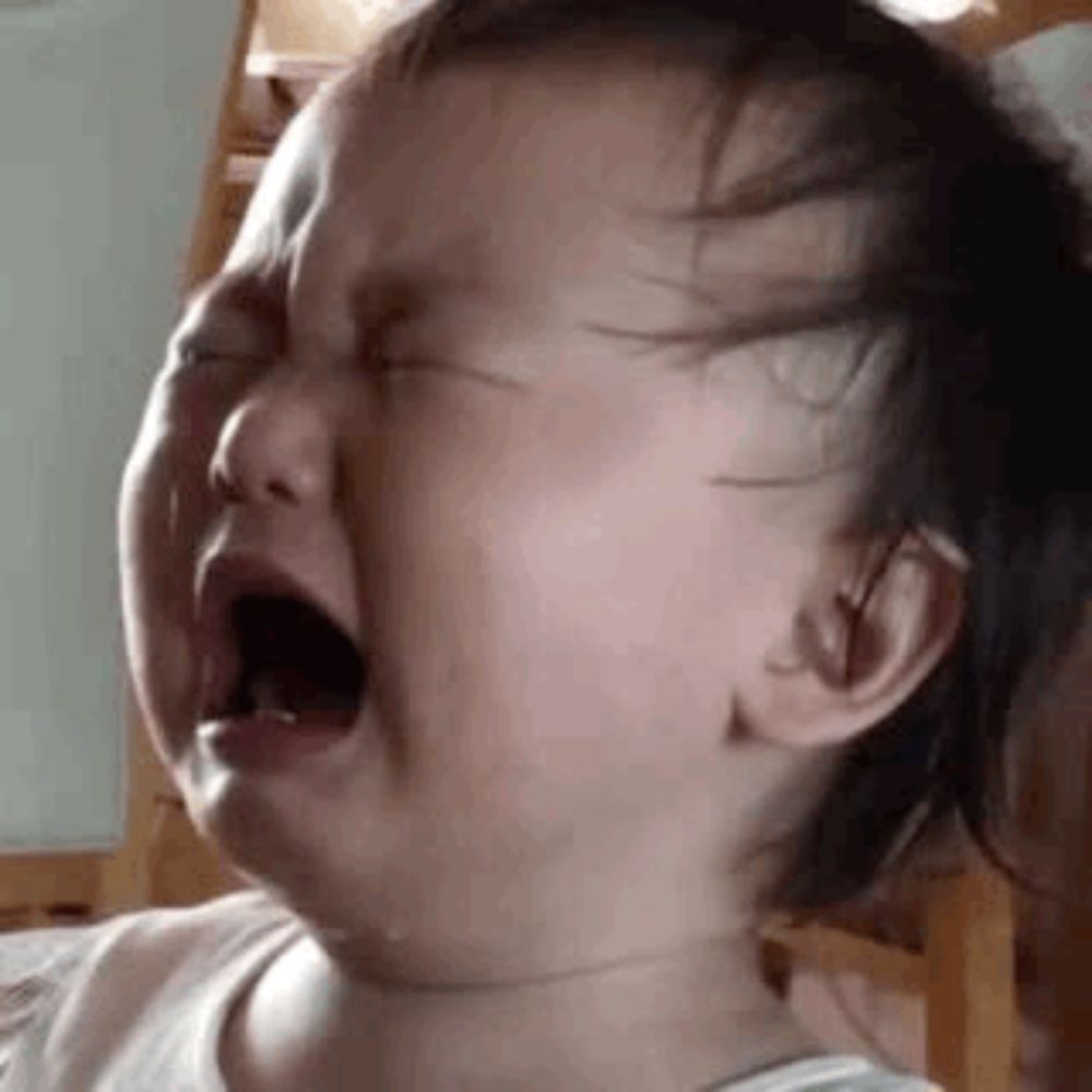 a baby is crying with his mouth open and tears coming out of his eyes .