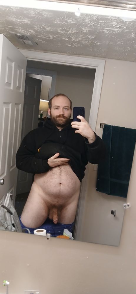 Reunan stands in the bathroom door frame with his pants down and jacket pulled up revealing his undercarriage.