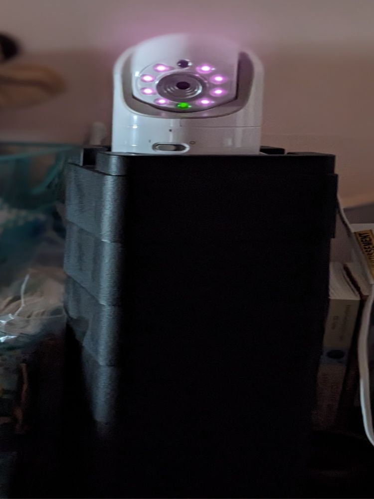 White baby monitor with ring of infrared lights on top of a plastic riser that looks like a black tower