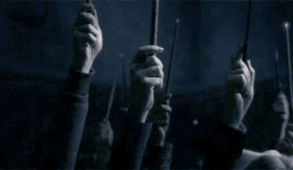 a group of people holding up their wands in the dark